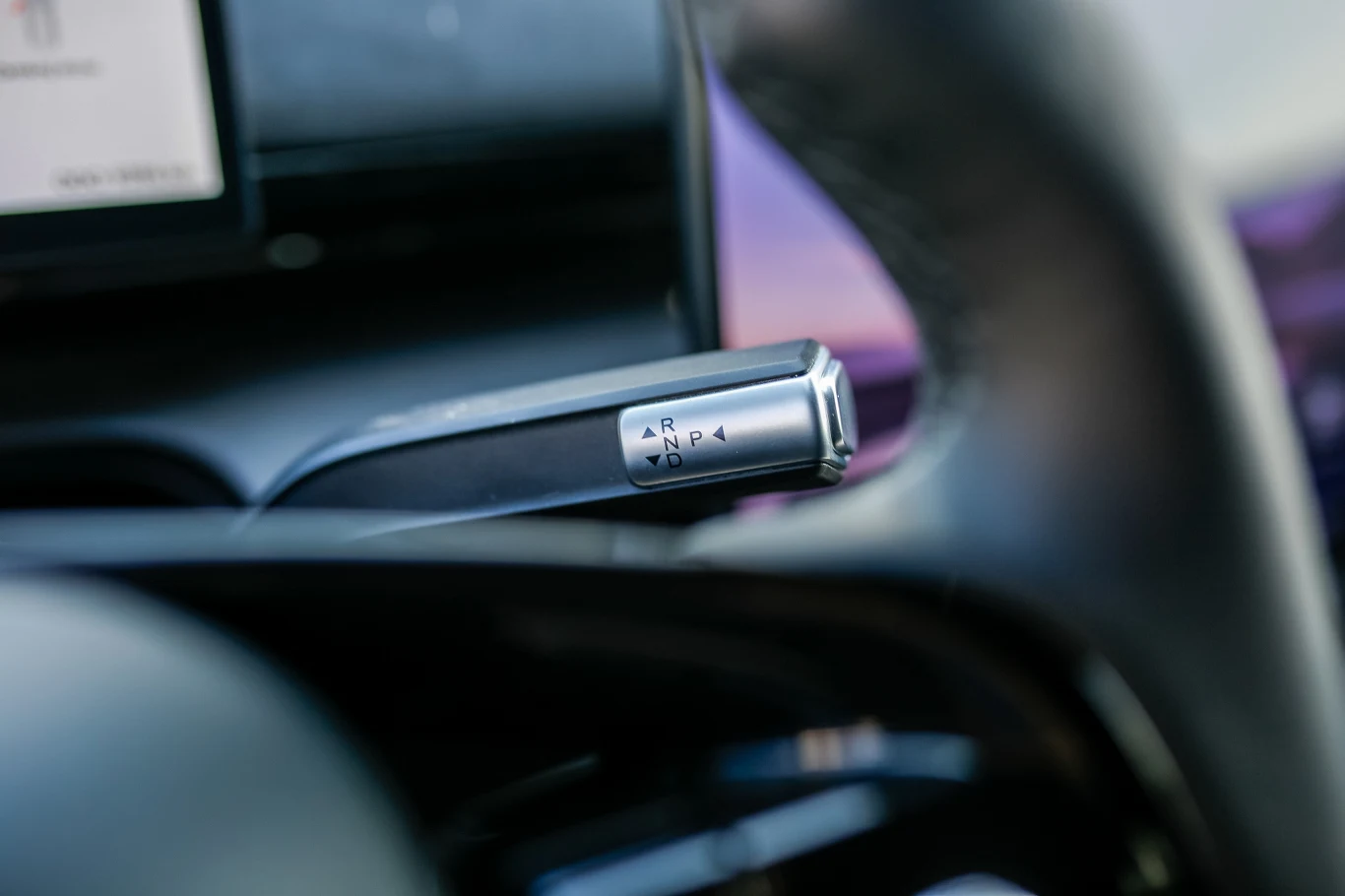 Omoda 7 Super Hybrid Dźwignia automatycznej skrzyni biegów z widocznymi oznaczeniami trybów jazdy umieszczona przy kierownicy samochodu.