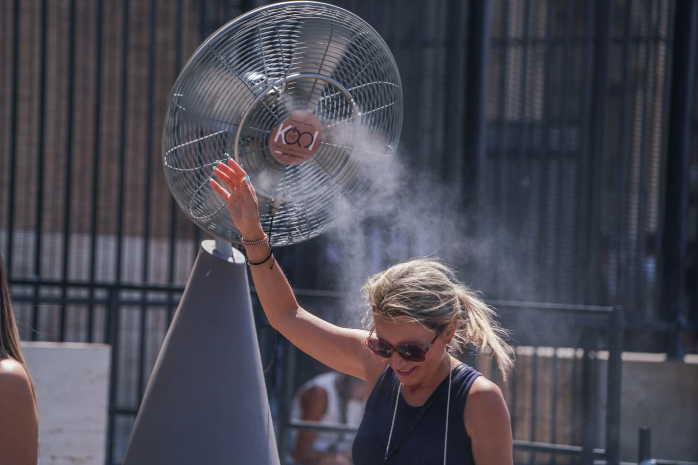 Temperatury we Włoszech przekraczają 40 stopni Kobieta chłodzi się przy wentylatorze z mgiełką wodną podczas upałów przekraczających 40 stopni we Włoszech.