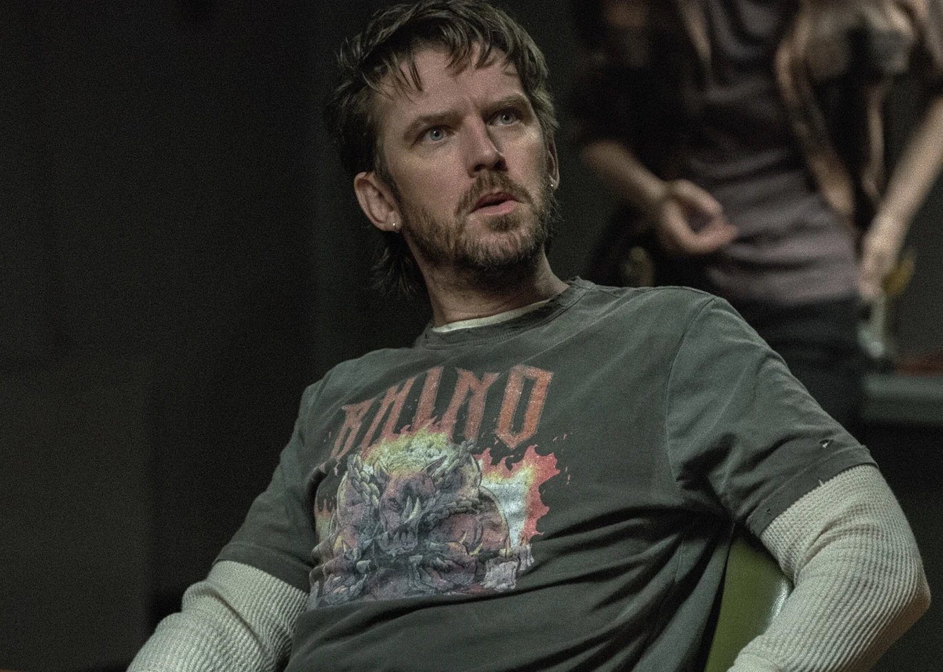 Dan Stevens w serialu "Terror: Devil in Silver" Dan Stevens jako Pepper w serialu "Terror: Devil in Silver" siedzi na krześle, ubrany w ciemnoszarą koszulkę i longsleeve.