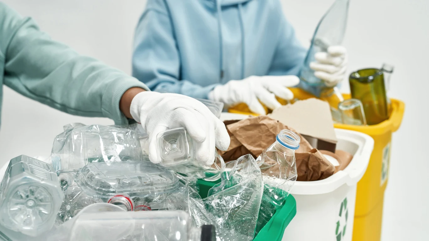 Plastik z cukru? Innowacyjne tworzywo. Ręce w białych rękawiczkach segregujące plastikowe odpady do oznaczonych pojemników na śmieci.