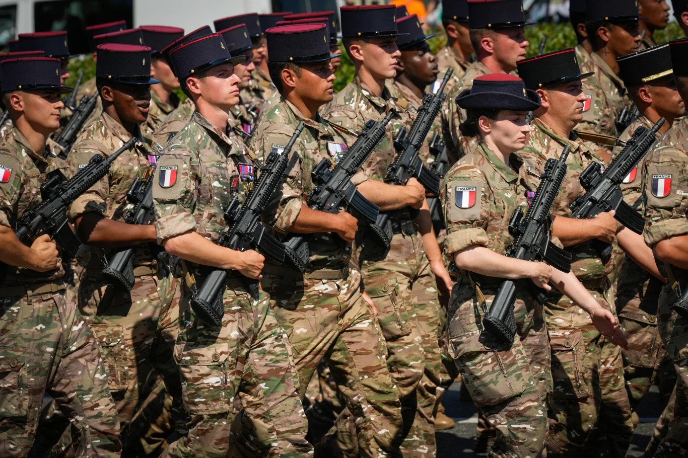 Sojusznicy z Francji zawsze gotowi do wsparcia Polski Grupa żołnierzy w mundurach maskujących i czapkach z czerwonymi lamówkami maszeruje w szyku, trzymając broń na ramieniu; na ramionach wyróżniają się naszywki z flagą Francji.