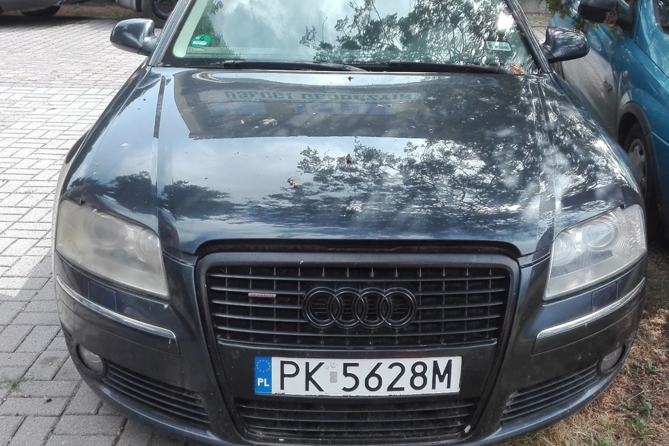Czarny samochód marki Audi z polską tablicą rejestracyjną PK 5628M zaparkowany na chodniku, widok z przodu.