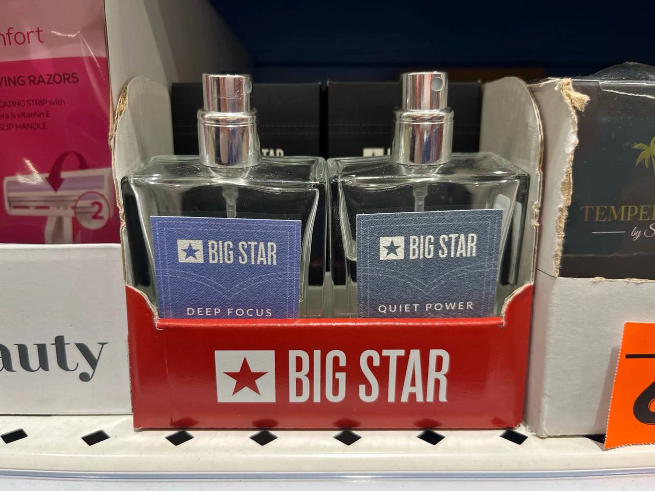 Wody toaletowe Big Star 50 ml aż66% taniej Dwie butelki perfum marki Big Star o nazwach Deep Focus i Quiet Power ustawione w czerwonym ekspozytorze z logo i nazwą producenta.