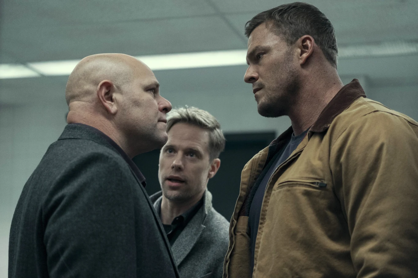 "Reacher" Dwóch mężczyzn stoi naprzeciw siebie, trzeci znajduje się pomiędzy nimi, w scenie z serialu „Reacher”.