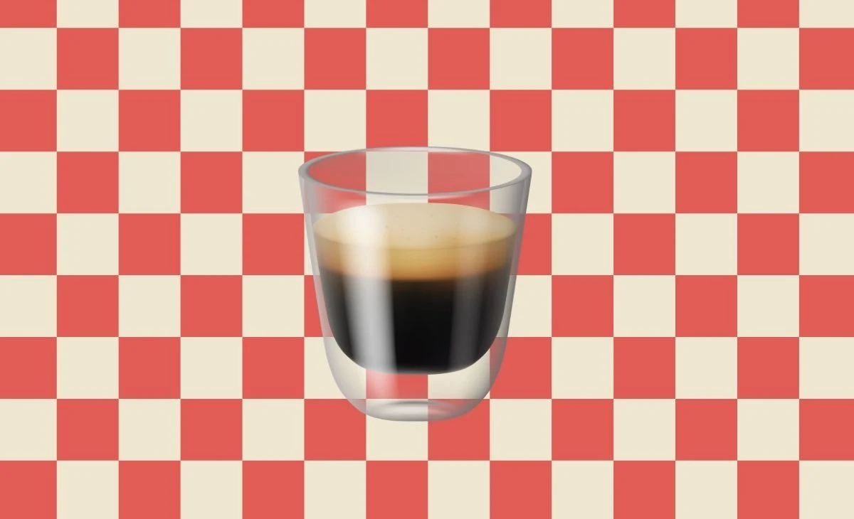 Wybrałaś espresso? Nie potrzebuję dodatków, żeby zrobić wrażenie Szklanka z espresso z kremową pianką ustawiona centralnie na tle czerwono-białej szachownicy.
