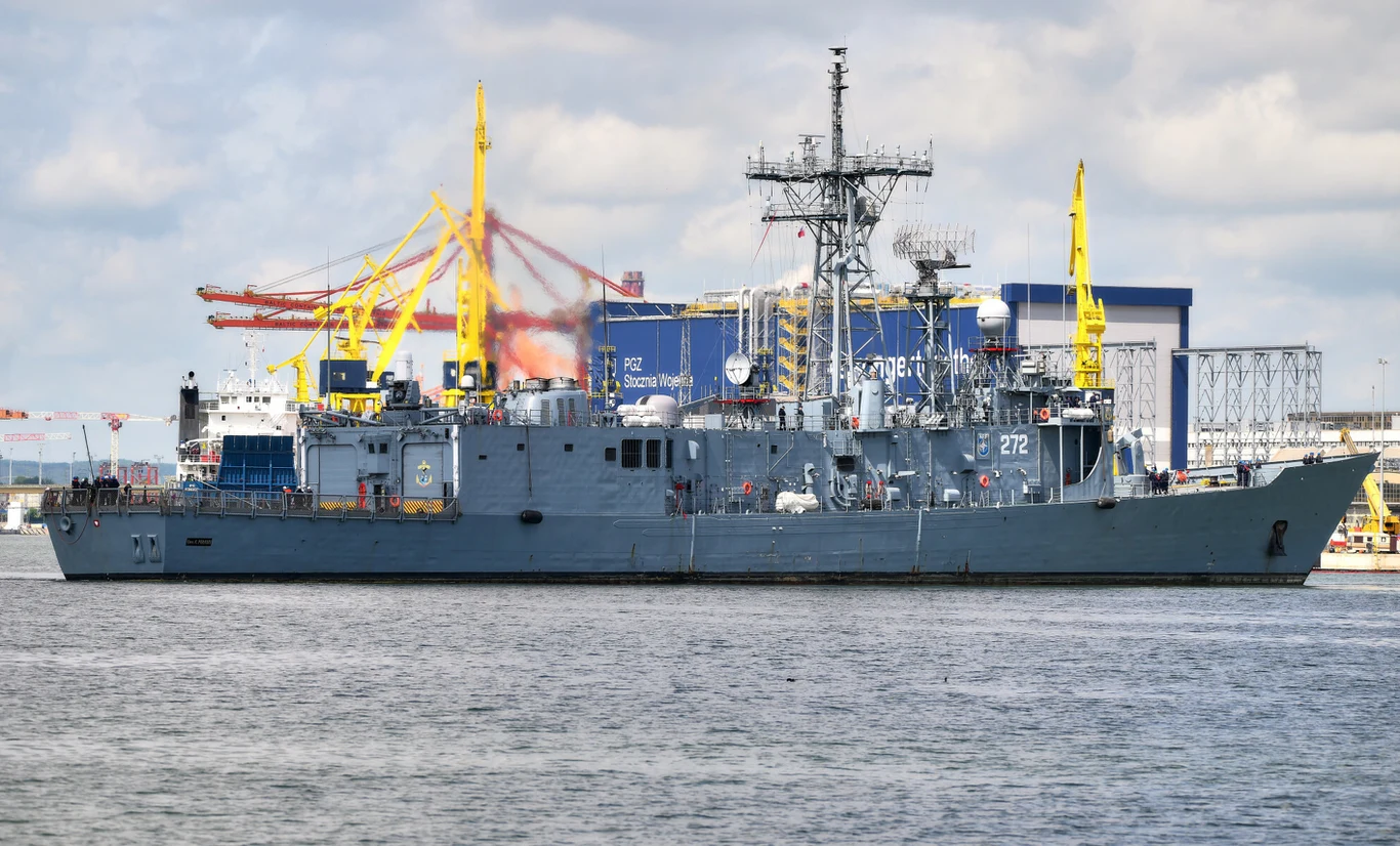 ORP Gen. K. Pulaski, jedna z dwóch wysłużonych, polskich fregat klasy OHP Szara okręt wojenny zacumowany w porcie, w tle żółte dźwigi stoczniowe oraz zabudowania przemysłowe.