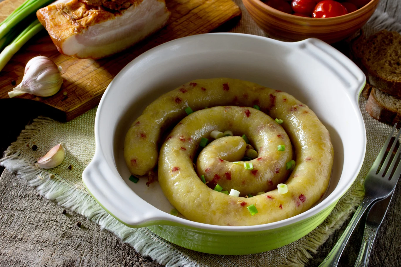 Kiszka ziemniaczana to swojski i tradycyjny przysmak Kiszka ziemniaczana w formie spirali w ceramicznym naczyniu, posypana szczypiorkiem, z cebulą, czosnkiem, boczkiem i chlebem.
