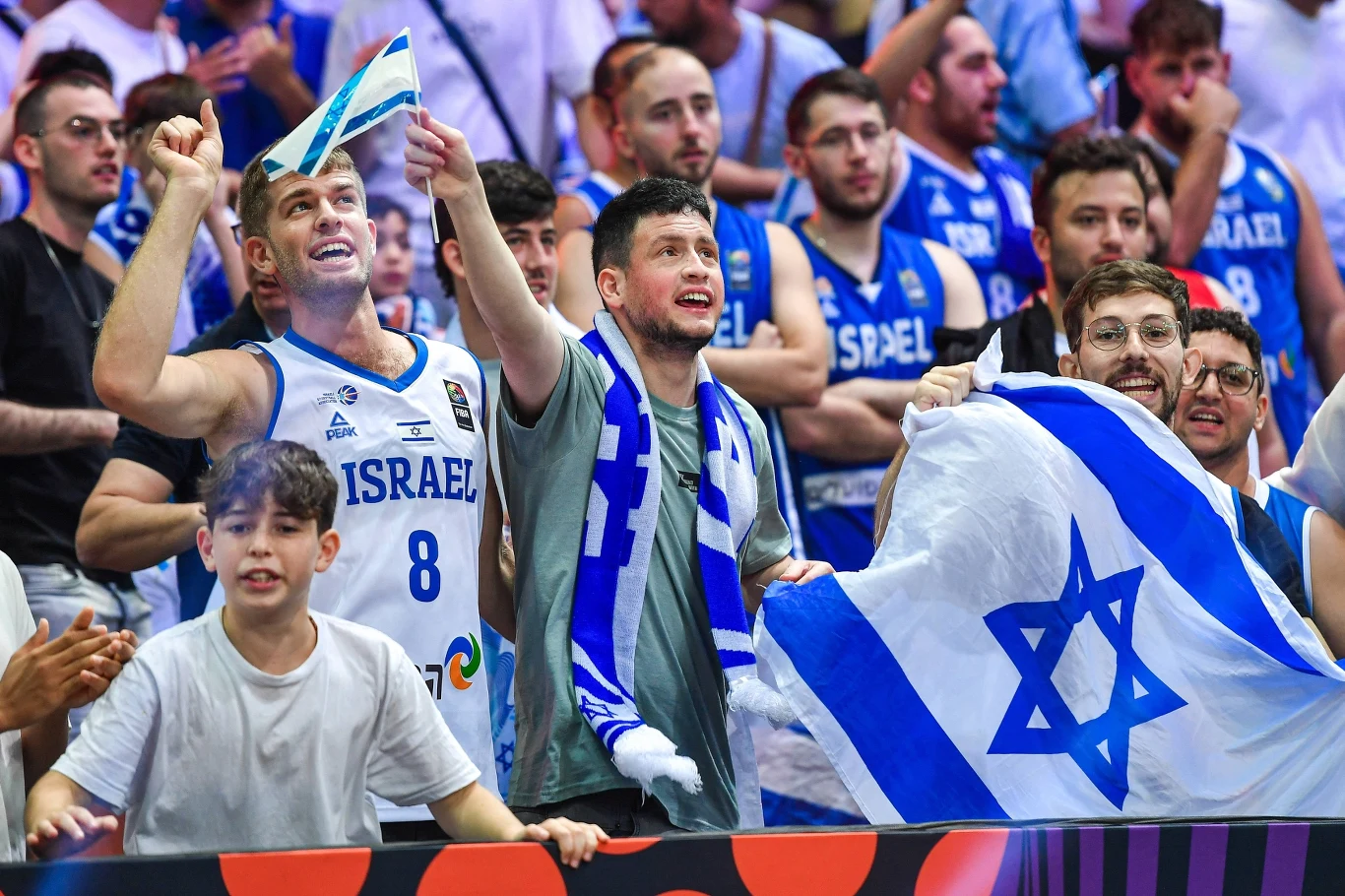 Izraelscy kibice Grupa izraelskich kibiców w niebiesko-białych barwach i z flagami Israel na wydarzeniu sportowym.