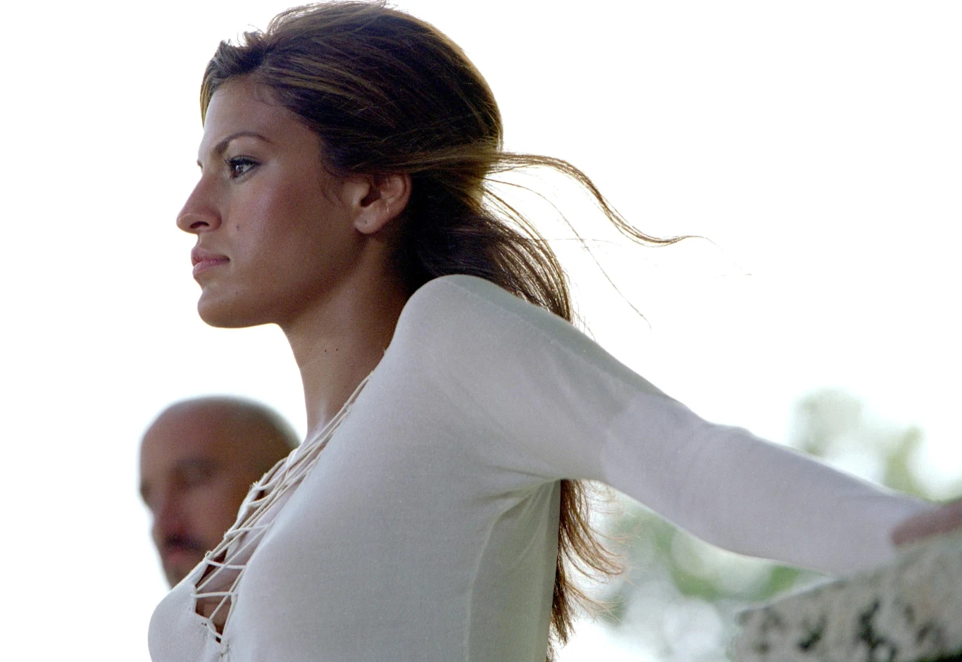 Eva Mendes w filmie "Za szybcy, za wściekli" Eva Mendes jako Monica Fuentes w białej bluzce, z profilu, w tle mężczyzna z ogoloną głową.