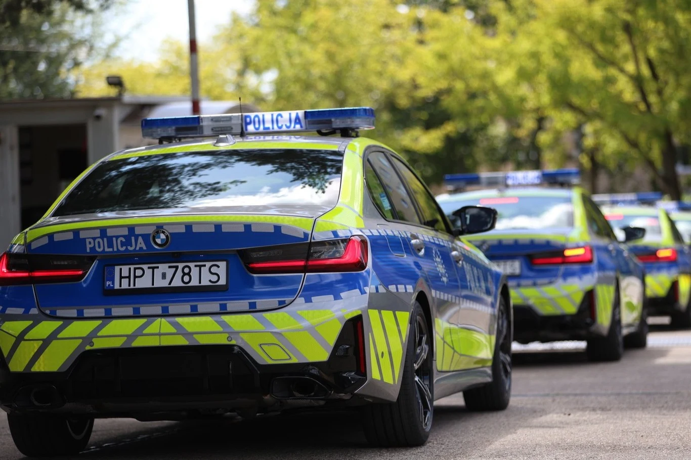 Nowe policyjne radiowozy rozpędzają się do 100 km/h w 4,3 s i mogą gnać z prędkością 250 km/h. Radiowozy policji w nowym oznakowaniu ustawione jeden za drugim na ulicy w słoneczny dzień.