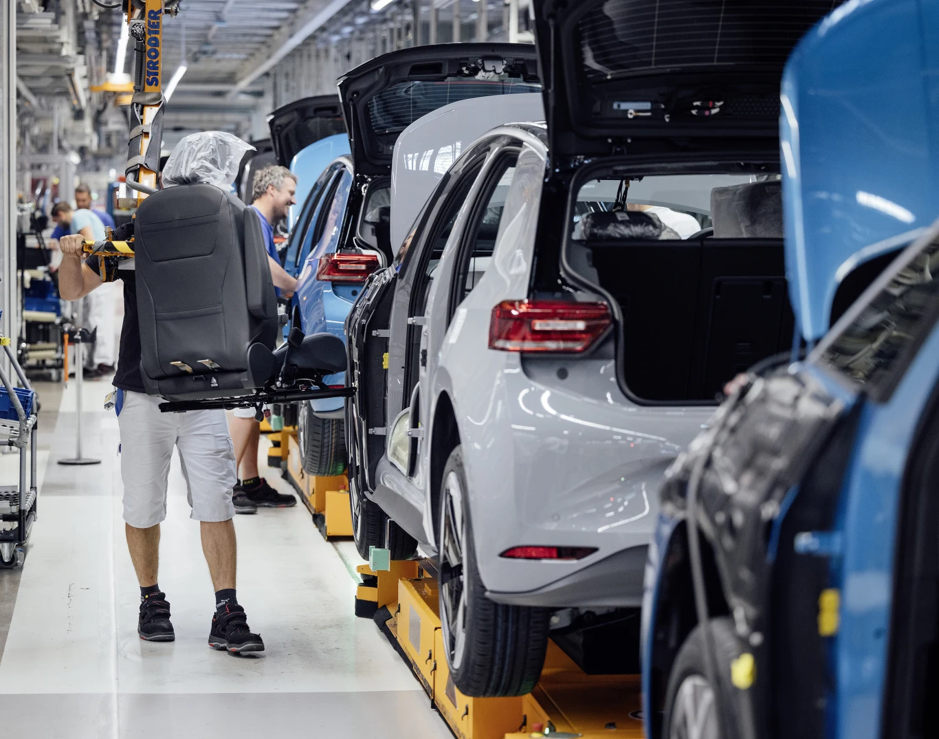 Produkcja Volkswagena ID.3 w fabryce w Zwickau Linia montażowa Volkswagena ID.3 w Zwickau, pracownik montuje siedzenie w nadwoziu pojazdu.