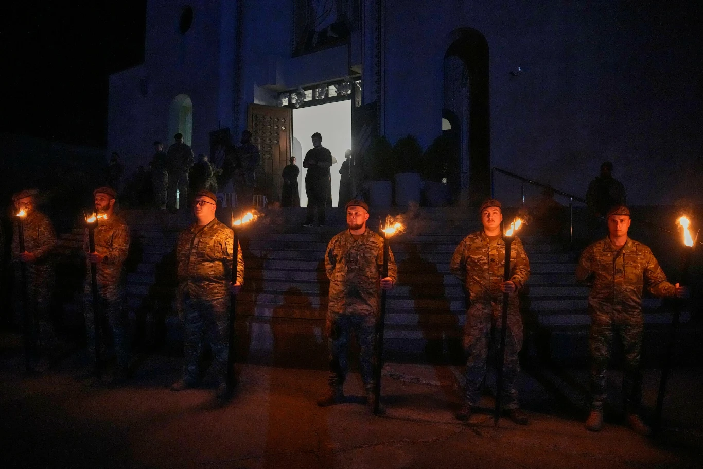 Trumna z prochami Konowalca wystawiona w Soborze Kościoła Greckokatolickiego w Kijowie Trumna z prochami Jewhena Konowalca na schodach Soboru w Kijowie; wojskowi z pochodniami stoją w szeregu.