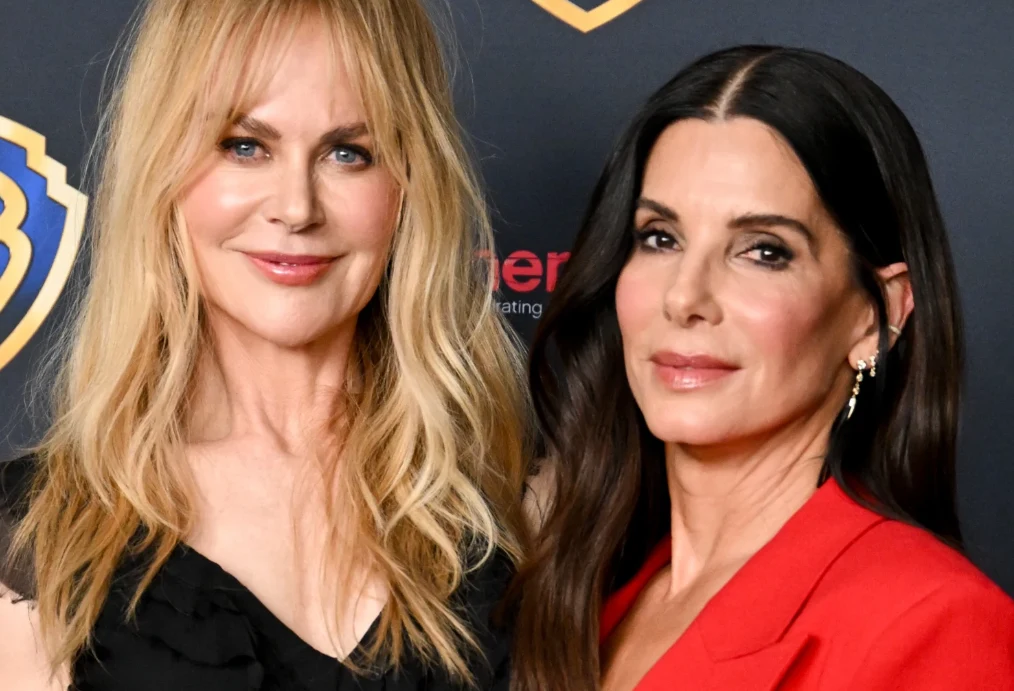 Nicole Kidman, Sandra Bullock Nicole Kidman i Sandra Bullock pozują razem, jedna w czarnej sukience, druga w czerwonej marynarce, na tle z logotypami.