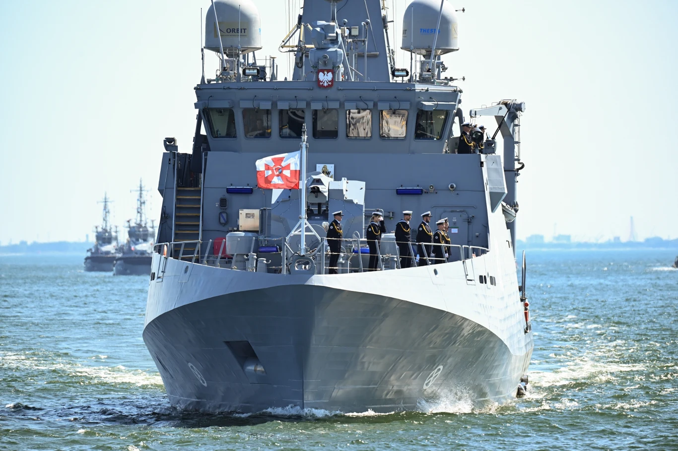 Parada Morska w Gdyni, W specjalnym szyku popłynie 20 jednostek Marynarki Wojennej RP i okrętów sojuszniczych Polski okręt wojenny płynący po spokojnej wodzie z załogą stojącą na dziobie, widoczną biało-czerwoną banderą marynarki i licznymi urządzeniami radarowymi na mostku.