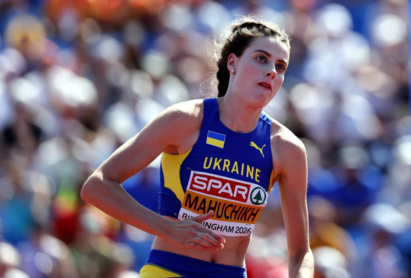 Zawodniczka z Ukrainy w sportowym stroju startowym podczas zawodów lekkoatletycznych, z tabliczką z nazwiskiem przypiętą do koszulki.