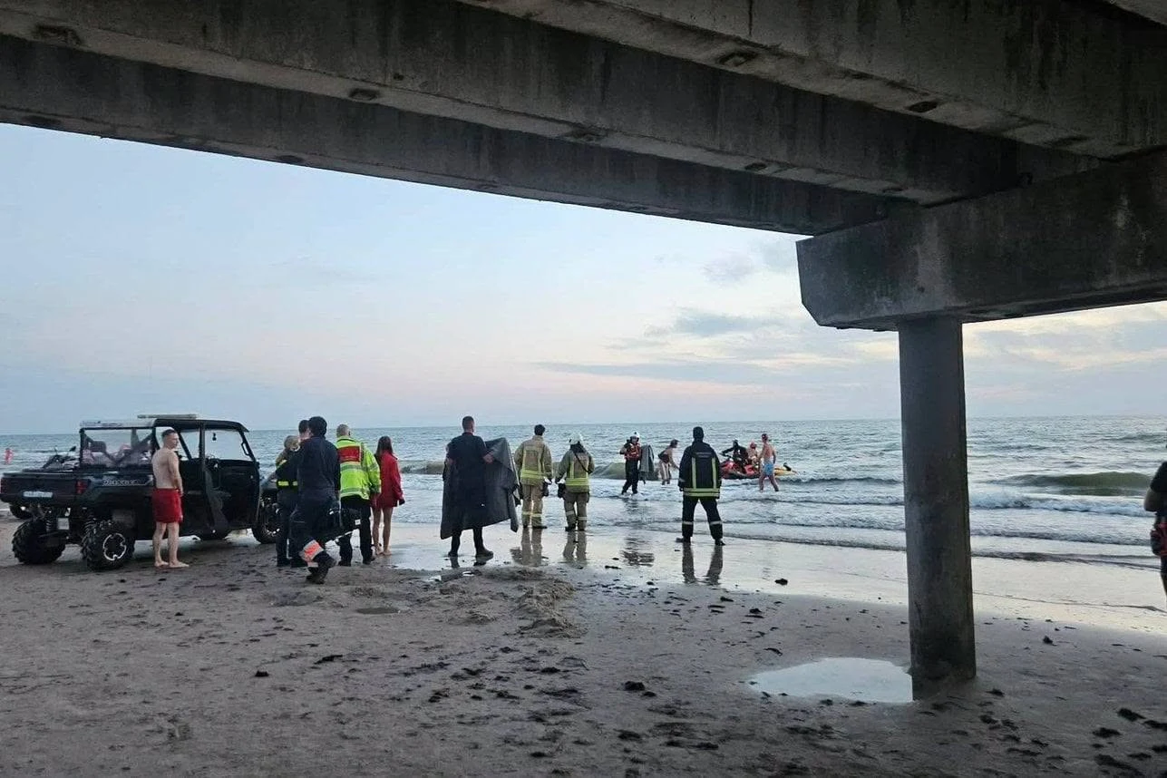 Litwa. W Połądze doszło do tragicznego wypadku. W Bałtyku utonął 17-latek Ratownicy wchodzą do morza pod Połągą, obok plaży stoi pojazd terenowy i mężczyzna w czerwonych szortach.