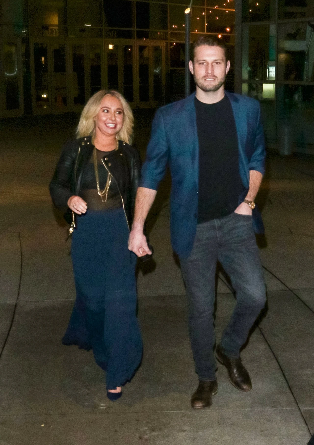 Hayden Panettiere i Brian Hickerson Kobieta w ciemnej, eleganckiej stylizacji i mężczyzna w granatowej marynarce trzymają się za ręce, idąc razem wieczorem po oświetlonym chodniku.
