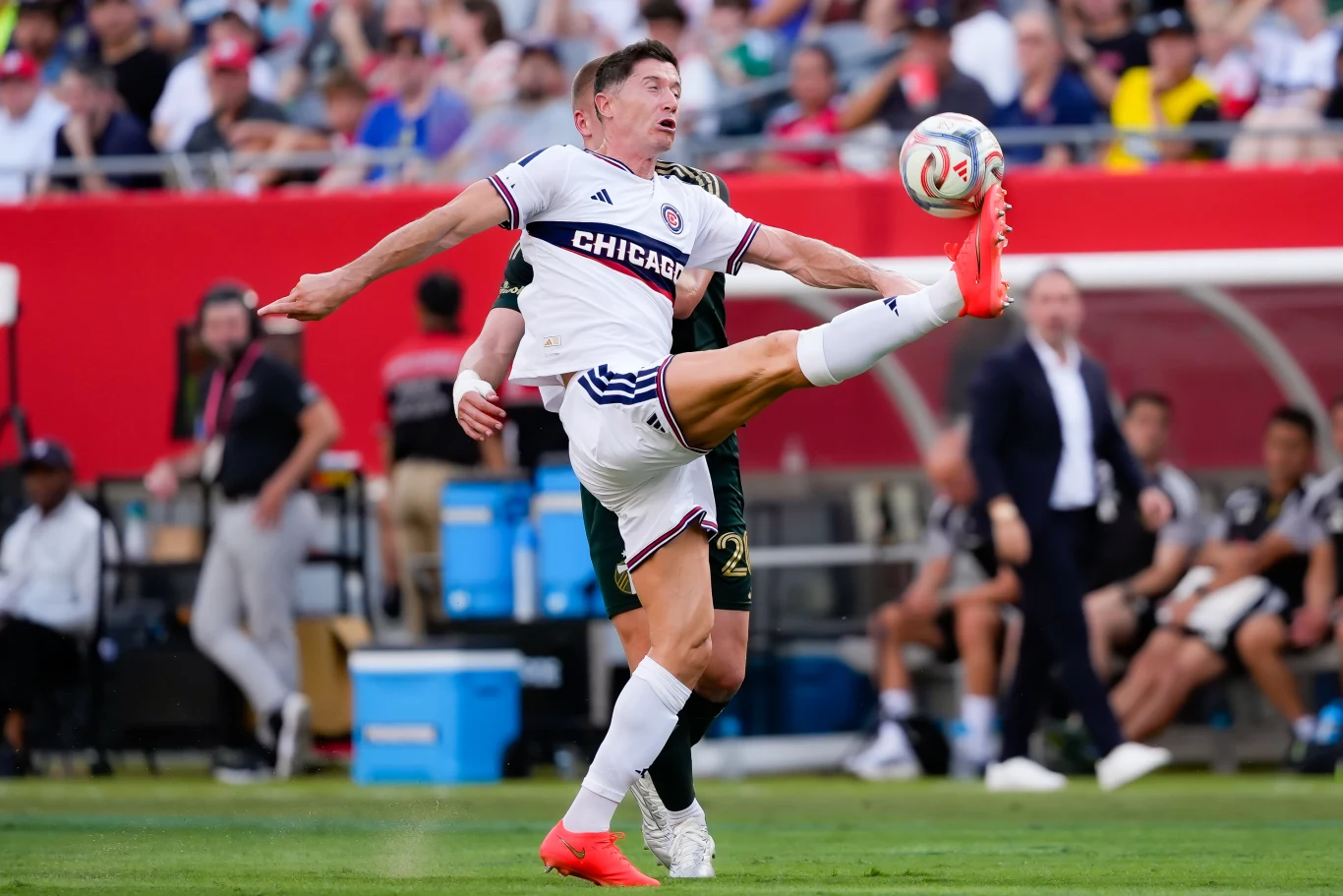 Robert Lewandowski w barwach Chicago Fire podczas meczu MLS Robert Lewandowski w białym stroju Chicago Fire podczas meczu MLS kopie piłkę na tle pełnych trybun.