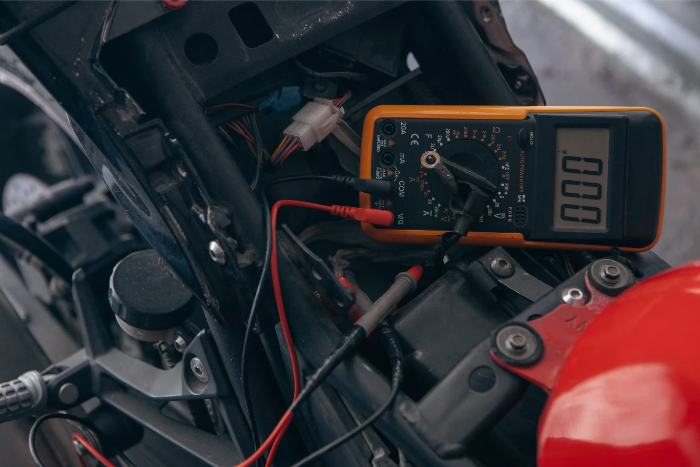 Stan akumulatora oraz ładowania można sprawdzić multimetrem. Cyfrowy multimetr podłączony do instalacji elektrycznej motocykla podczas pomiarów diagnostycznych.