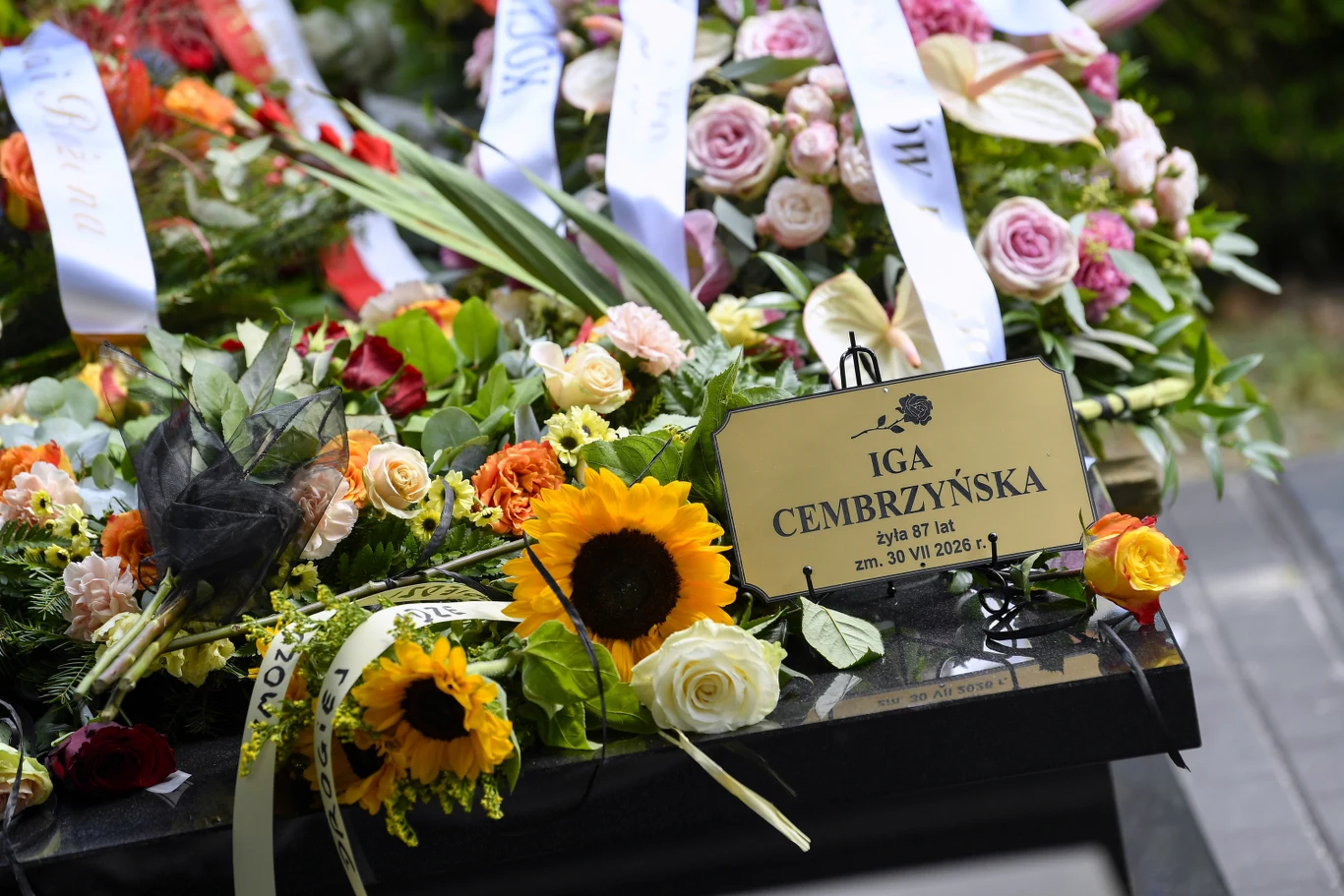 Pogrzeb Igi Cembrzyńskiej Nagrobek pokryty licznymi kolorowymi kwiatami i wiązankami z widoczną tabliczką z imieniem i nazwiskiem Igi Cembrzyńskiej oraz datą śmierci.