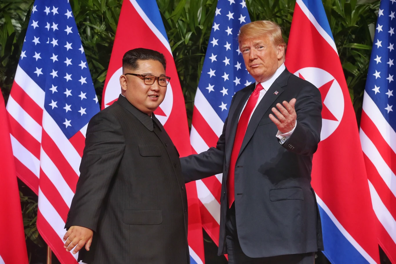 Spotkanie Trumpa i Kima w Singapurze. Zdjęcie z 2018 roku Donald Trump i Kim Dzong Un stoją obok siebie na tle flag USA i Korei Północnej podczas spotkania w 2018 roku.