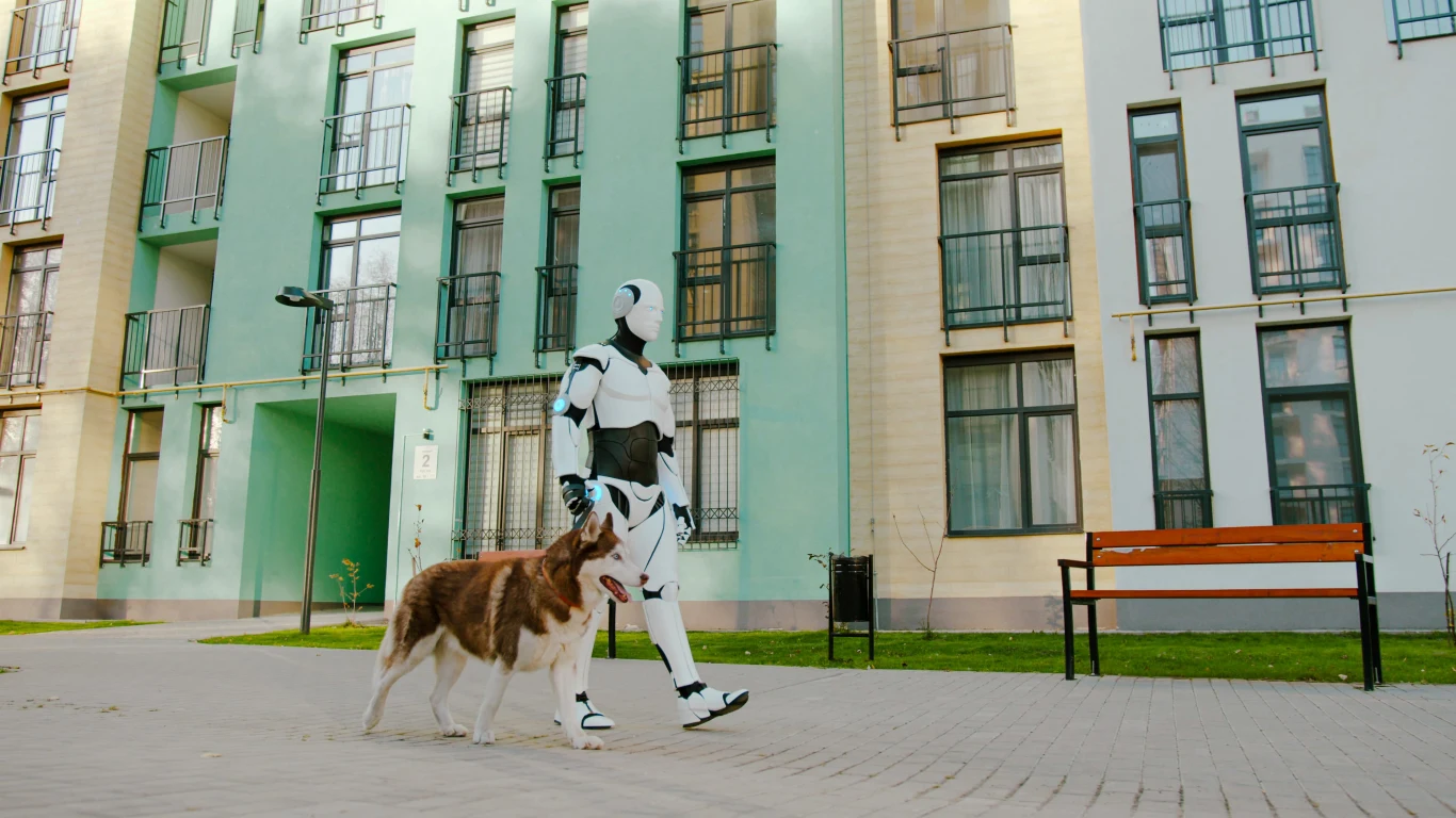 Robot w futurystycznym stroju prowadzi psa na smyczy chodnikiem przed blokiem mieszkalnym, obok znajduje się pusta ławka.