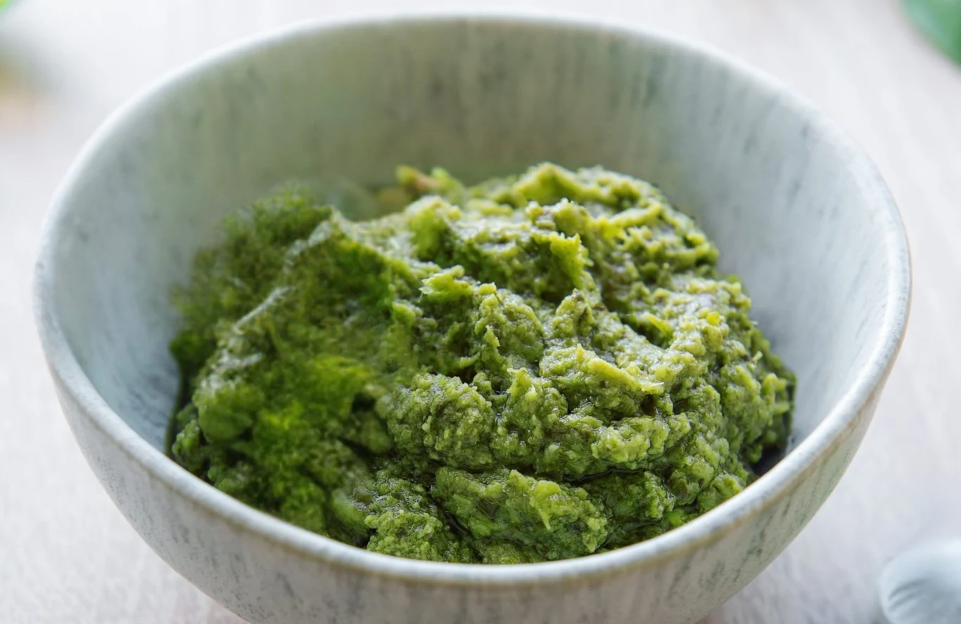Cukinia może być dobrą bazą do domowego pesto Porcja pesto z cukinii o kremowej konsystencji w jasnej miseczce na jasnym tle.
