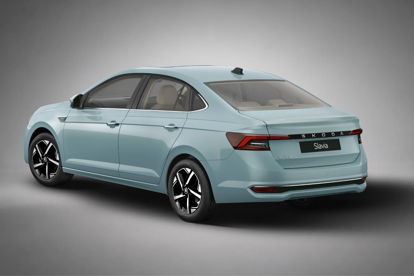 Jasnoniebieski sedan Skoda Slavia z czarnymi, pięcioramiennymi felgami widoczny z tyłu pod kątem, w minimalistycznym otoczeniu bez wyraźnych elementów tła.