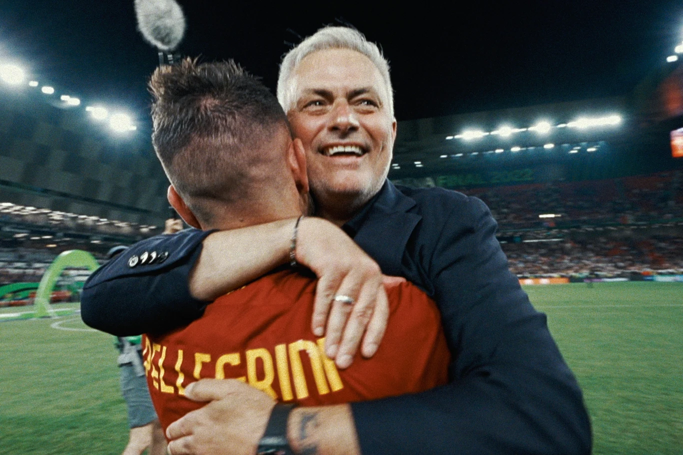 "José Mourinho" José Mourinho w garniturze obejmuje piłkarza w czerwonej koszulce na stadionie podczas świętowania.