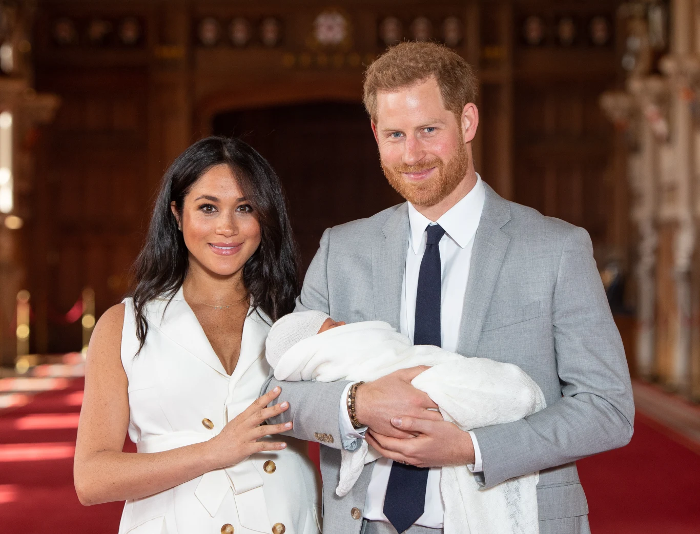 Na temat historii związanej z nadaniem takiego, a nie innego imienia córce Meghan i Harry'ego krąży wiele historii Para ubrana elegancko pozuje w przestronnym, bogato zdobionym wnętrzu, trzymając w ramionach niemowlę owinięte w biały kocyk.