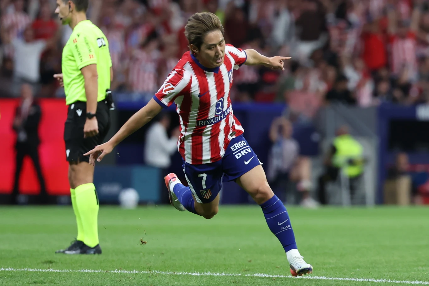 Lee Kang-in, pozyskany tego lata z PSG, zaliczył udany debiut w barwach Atletico Piłkarka w koszulce Atlético Madryt świętuje zdobycie gola, rozkładając ręce podczas meczu, w tle widoczny sędzia i kibice na trybunach.