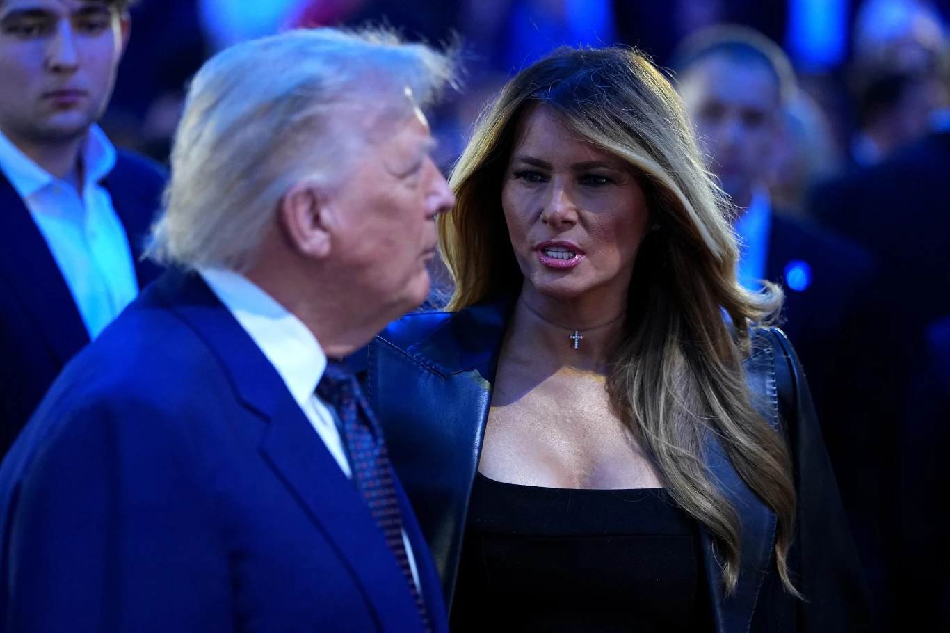 Pojawia się coraz więcej pytań o pozycję Melanii Trump zarówno jako żony, jak i pierwszej damy Kobieta w ciemnym ubraniu i z długimi włosami rozmawia z mężczyzną ubranym w garnitur na tle tłumu osób w niebieskim świetle.