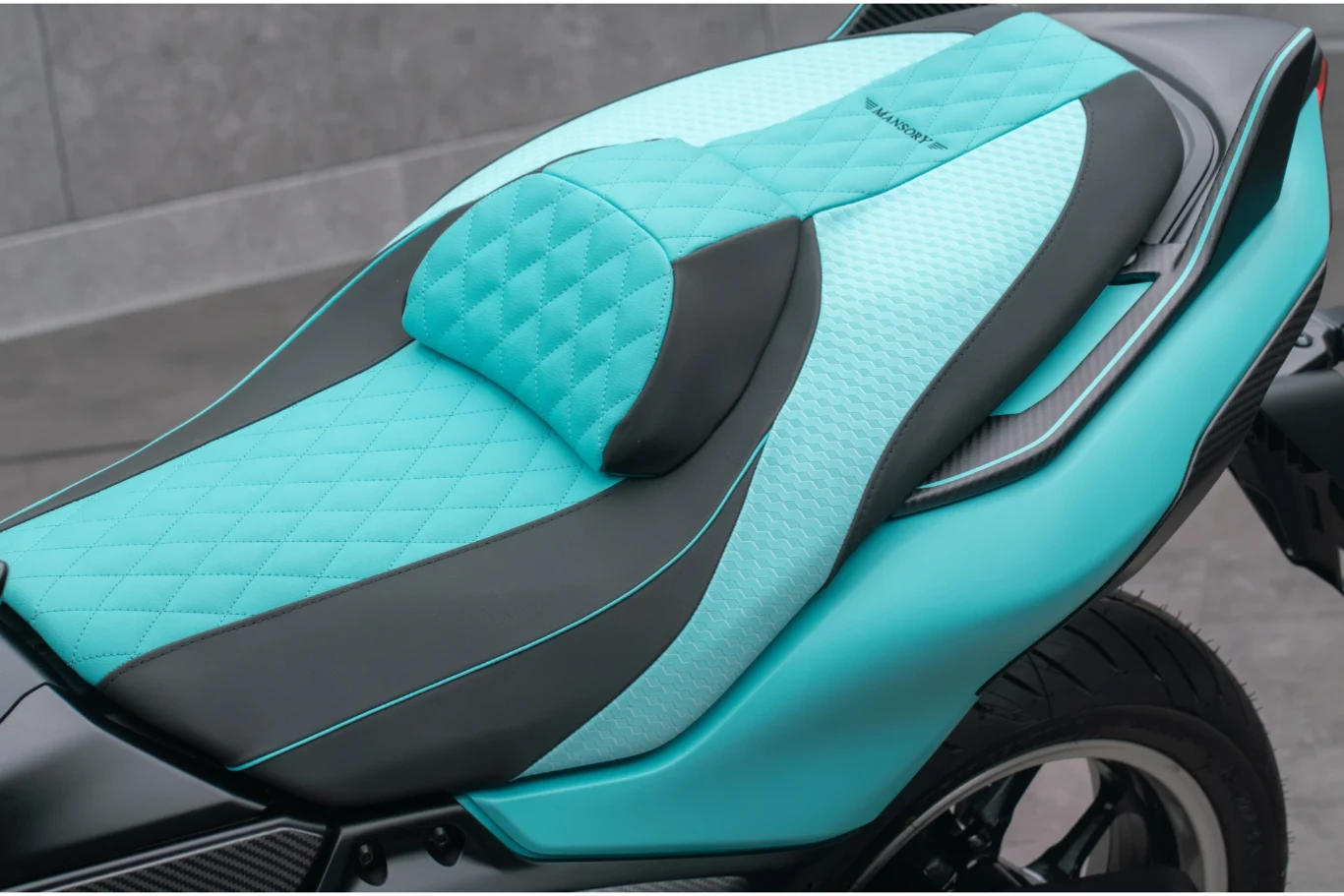 Turkusowo-czarna, pikowana kanapa motocykla z eleganckim przeszyciem i wygodnym oparciem dla pasażera.