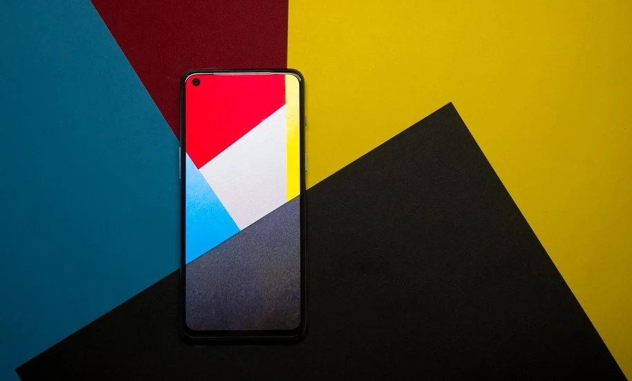 Tani smartfon na kolorowym tle Smartfon leżący na kolorowym geometrycznym tle