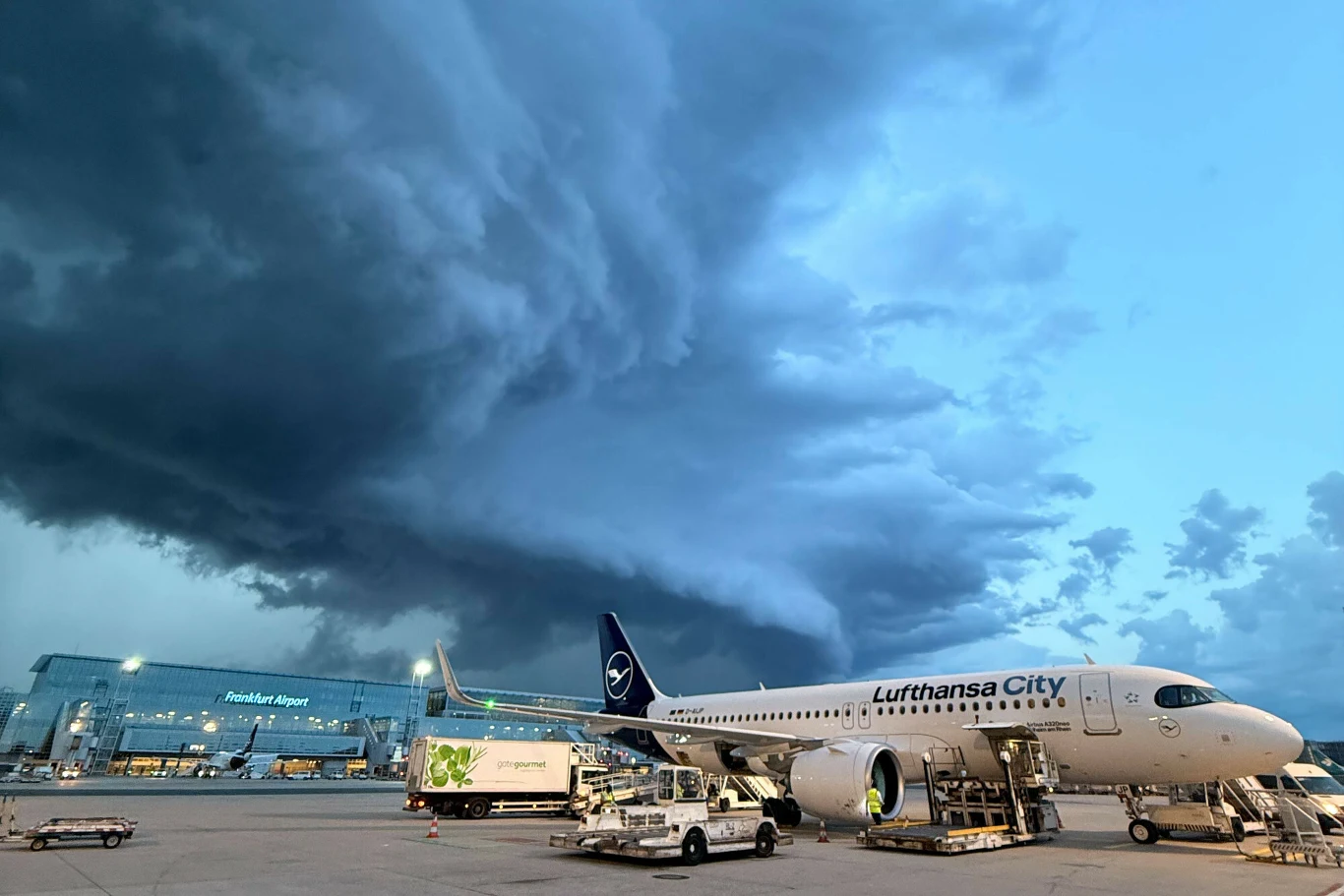 Komórka burzowa formująca się w rejonie lotniska we Frankfurcie nad Menem. Niebezpieczne nawałnice przeszły przez wiele niemieckich miast Samolot pasażerski Lufthansa CityLine przygotowywany do odlotu na płycie lotniska, nad którym gromadzą się ciemne, burzowe chmury.