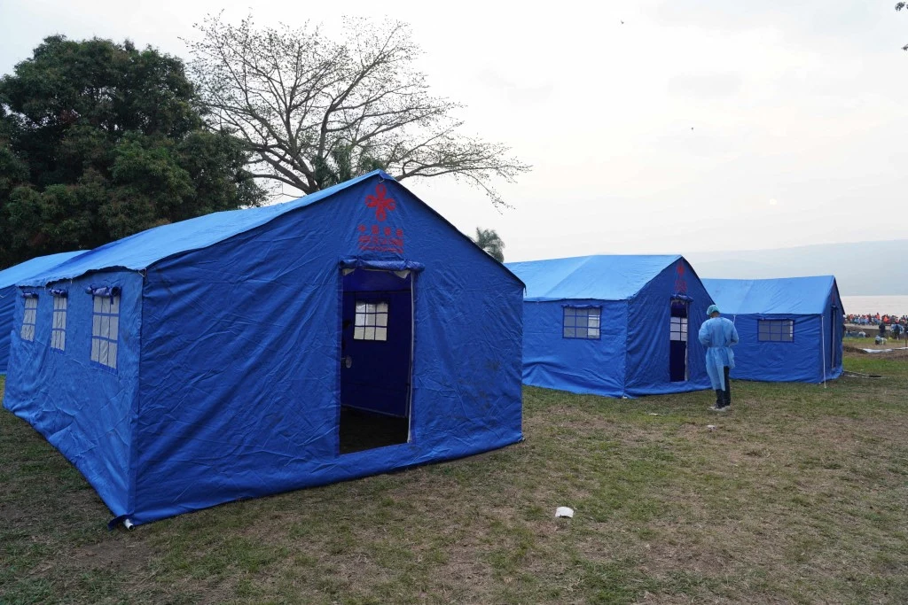 Epidemia wirusa Ebola w DRK. Zmarło 2500 osób, połowa z nich w ciągu ostatnich 14 dni Trzy niebieskie namioty medyczne na trawie, osoba w niebieskim kombinezonie wchodzi do namiotu, DRK, epidemia Eboli.