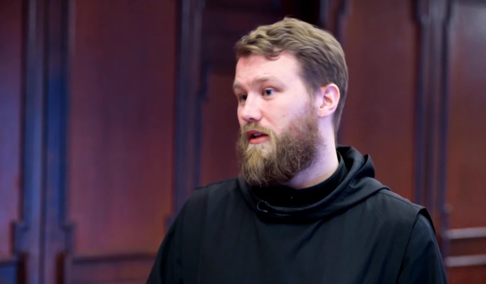 O. Karol Mężczyzna z brodą w ciemnym habicie na tle drewnianej boazerii.