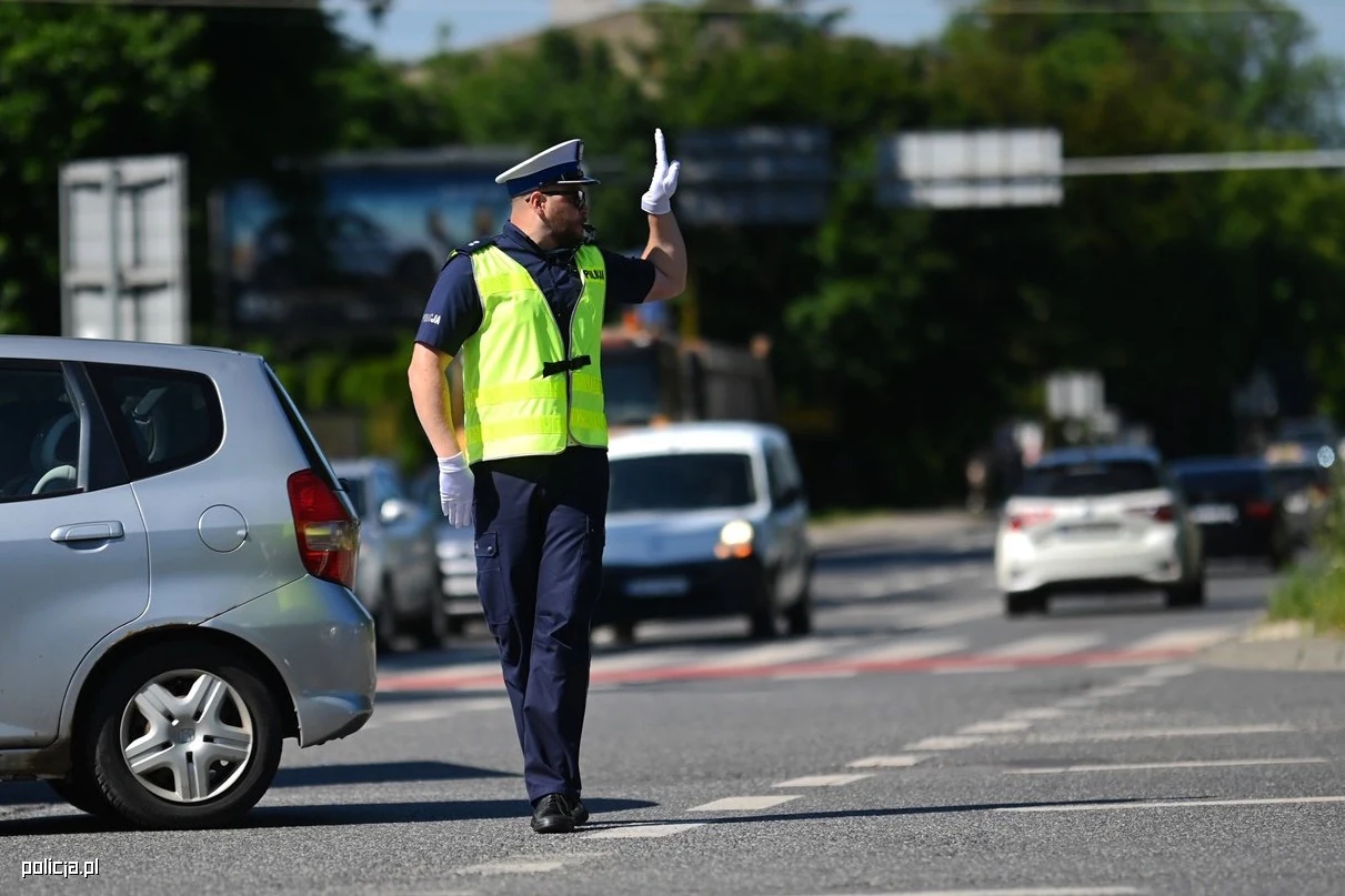 Nie każdą sytuację drogową da się łatwo zinterpretować Policjant w kamizelce odblaskowej reguluje ruch na skrzyżowaniu, unosi rękę w stronę pojazdów.