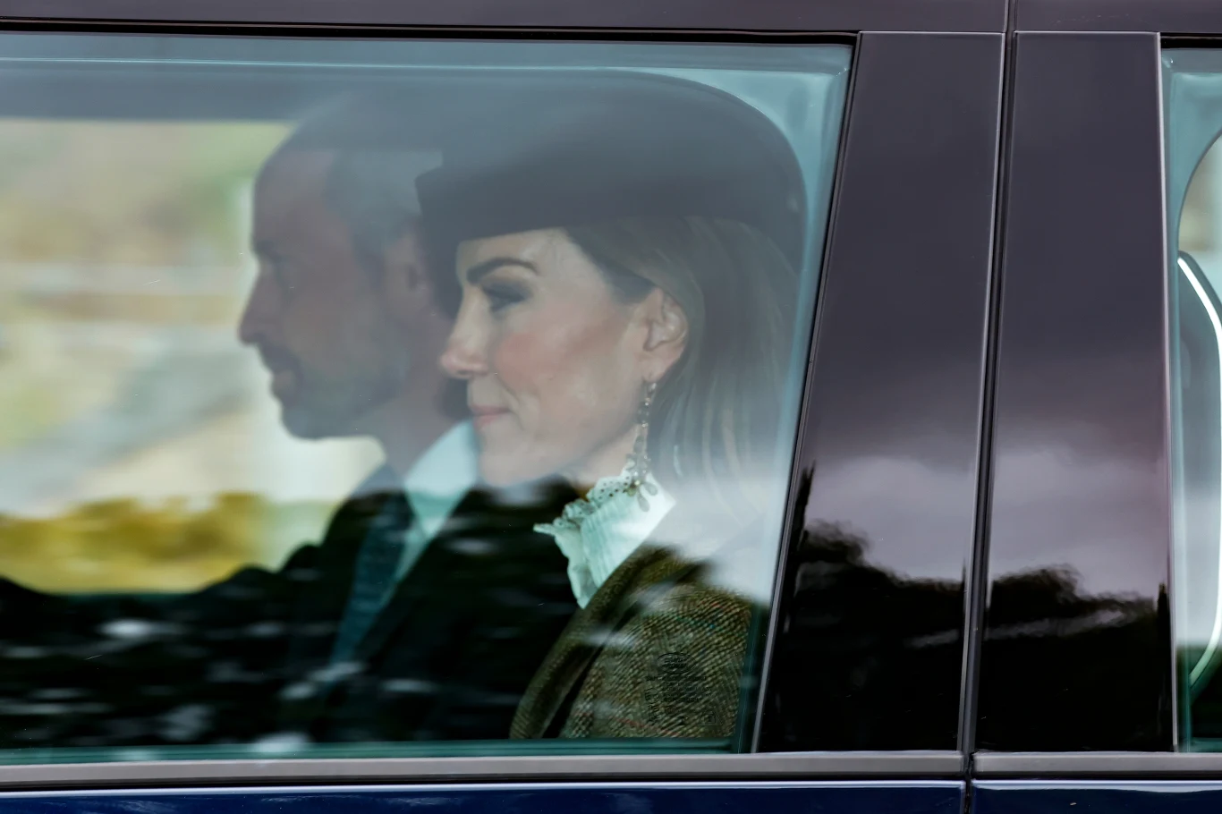 Uwaga publiczna jest ciekawa reakcji Kate i Williama na powrót Harry'ego i Meghan do Wielkiej Brytanii Dwie elegancko ubrane osoby siedzące obok siebie wewnątrz samochodu, widoczne przez szybę pojazdu.