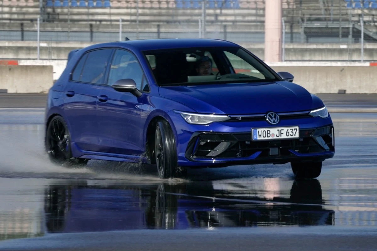 Golfem R miałem okazję jeździć wielokrotnie Niebieski Volkswagen Golf R w trakcie dynamicznej jazdy po mokrej nawierzchni, przednie koła skręcone, woda rozpryskuje się spod opon.