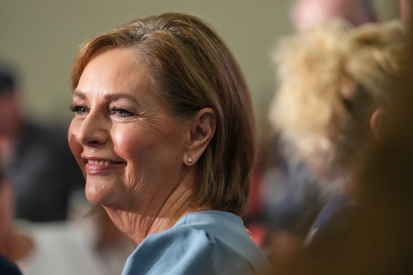 Darline Graham walczy o miejsce Senacie po śmierci brata - senatora Lindseya Grahama Uśmiechnięta Darline Graham w jasnoniebieskiej bluzce, ukazana z profilu na pierwszym planie, w otoczeniu innych osób w lekko rozmytym tle.
