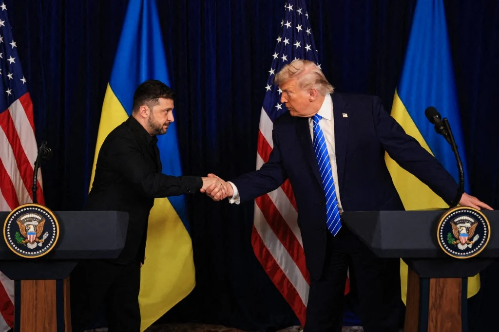 Wołodymyr Zełenski otrzymał list od Donalda Trumpa Wołodymyr Zełenski i Donald Trump ściskają dłonie na tle flag Ukrainy i USA przy mównicach prezydenckich.