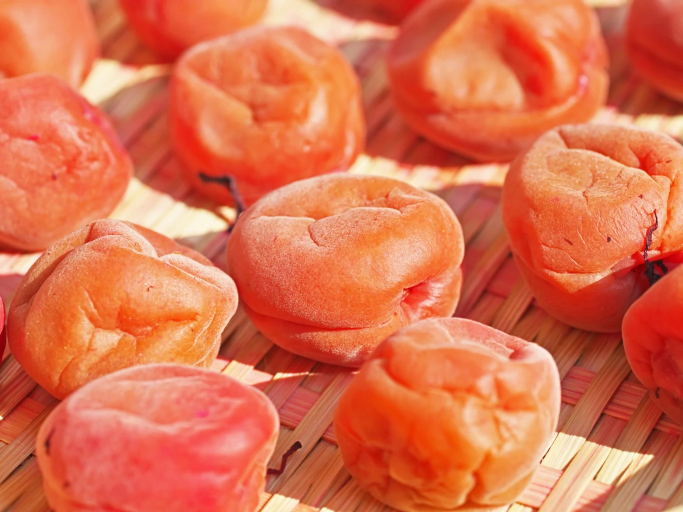 Śliwki umeboshi to jeden z sekretów długowieczności mieszkańców japońskiej Okinawy Śliwka umeboshi o pomarszczonej skórce na plecionej macie, tradycyjny produkt z Japonii.
