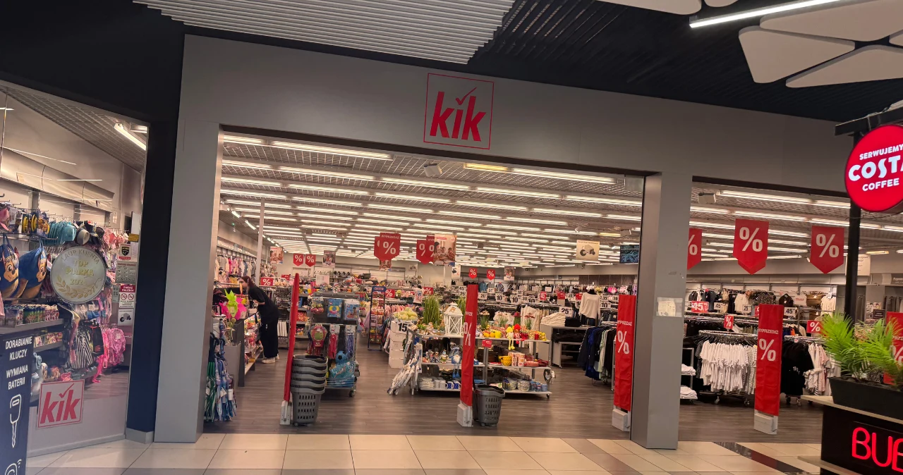 KiK pokazał nową kolekcję na jesień. Ceny zaczynają się od 7 zł Wejście do sklepu KiK z asortymentem odzieży i akcesoriów, widoczne czerwone tablice z oznaczeniami promocji.
