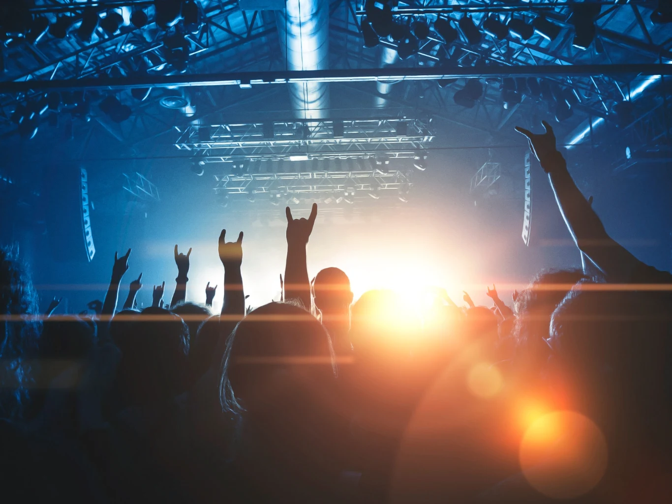 Fani heavy metalu lepiej znoszą ból. Wyniki badania zaskakują Tłum fanów heavy metalu z uniesionymi rękami podczas koncertu, silne światła sceniczne w tle.