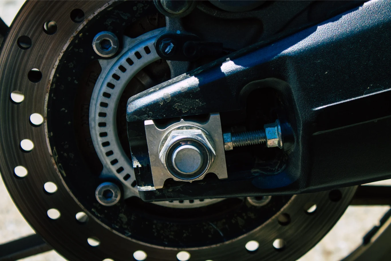 Fragment tylnego koła motocykla z dobrze widocznym mechanizmem hamulcowym i detalami montażowymi.