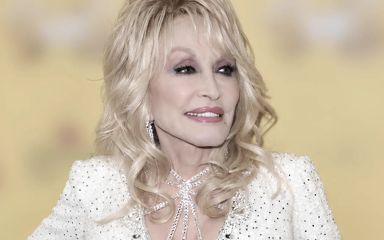 Dolly Parton Dolly Parton w ozdobionej z burzą falowanych włosów, delikatnym makijażem i kolczykami, uśmiechnięta na żółtym tle.
