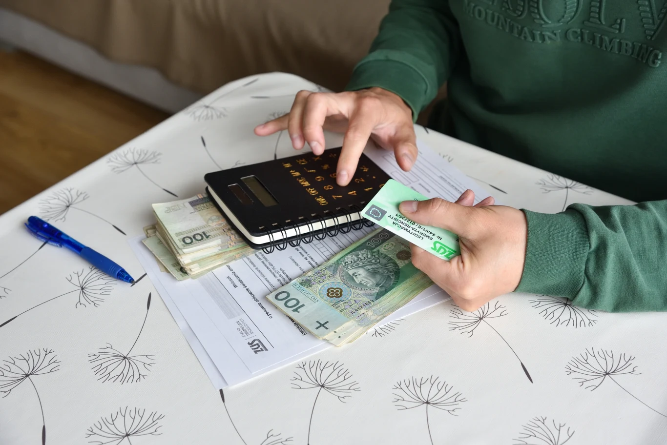 Ten formularz może podnieść emeryturę. Zyskają tylko niektórzy seniorzy Osoba liczy polskie banknoty kalkulatorem, obok widoczne dokumenty EPD-21 i długopis.