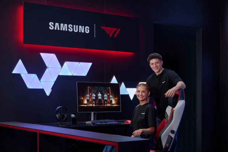 Na tegorocznych targach Gamescom Samsung przedstawi m.in. nową linię monitorów gamingowych z serii Odyssey na 2027 rok Dwie osoby w czarnych koszulkach w nowoczesnym pokoju gamingowym, siedząca przy biurku z monitorem i sprzętem komputerowym, podświetlenie LED oraz duże logo Samsung i T1 na ścianie.