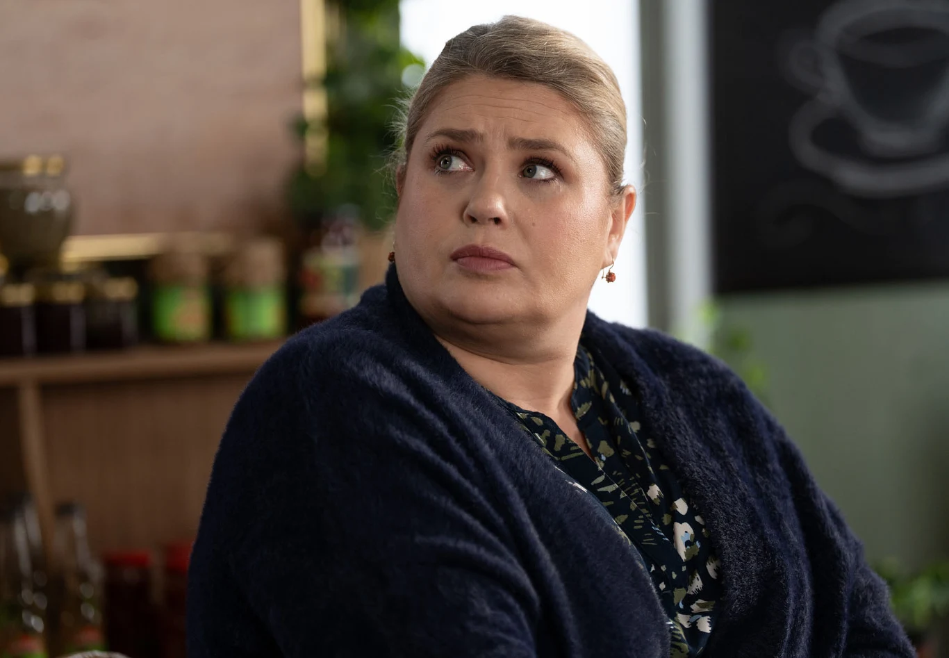 Aldona obieca Elżbiecie, że w każdej chwili mogą przyjąć młodych do siebie Kobieta o jasnych włosach spiętych w kok, ubrana w granatowy sweter i wzorzystą bluzkę, siedzi i spogląda w bok z poważnym wyrazem twarzy.